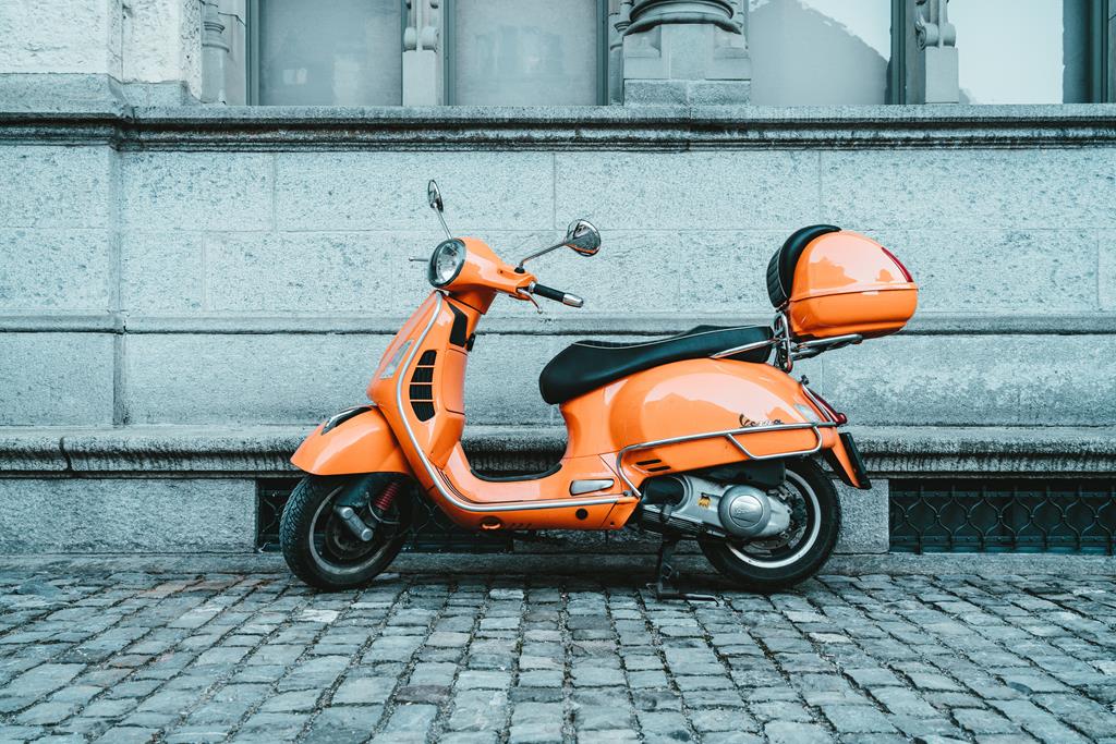 scooter laranja estacionada perto de um muro