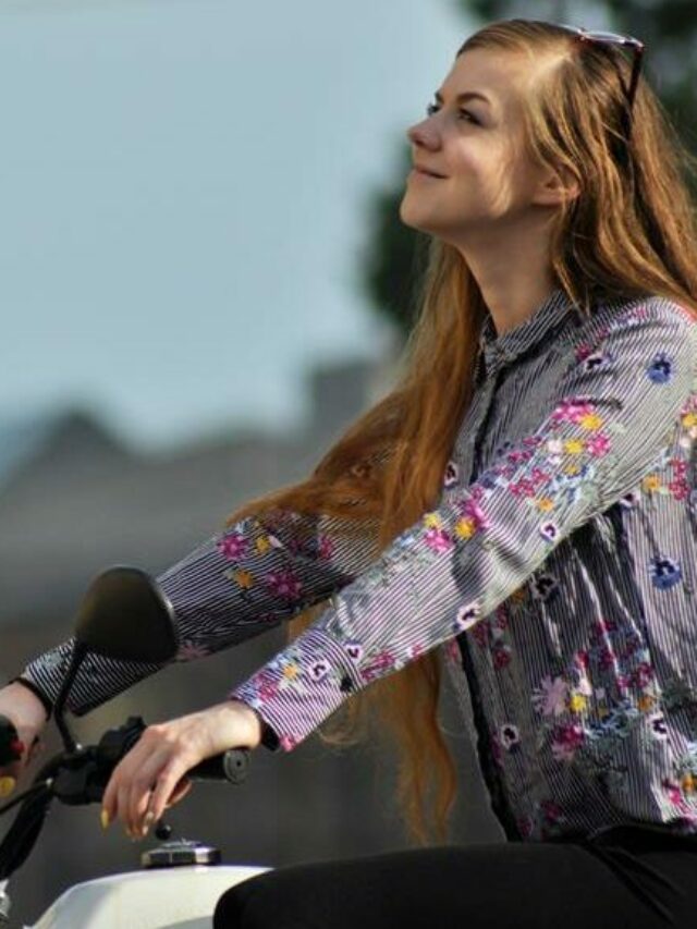 mulher ruiva montada na moto, sorrindo e olhando para cima