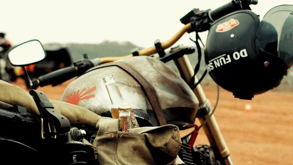 Capacete pendurado no guidão e moto empoeirada