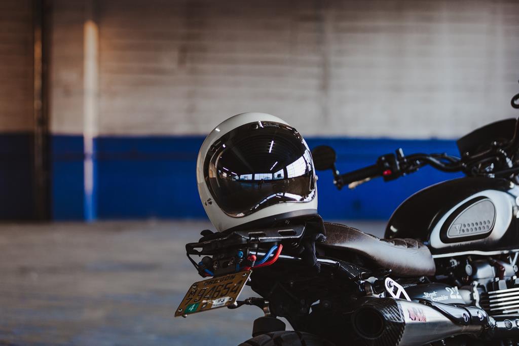 capacete branco em com viseira preta cima do banco da moto