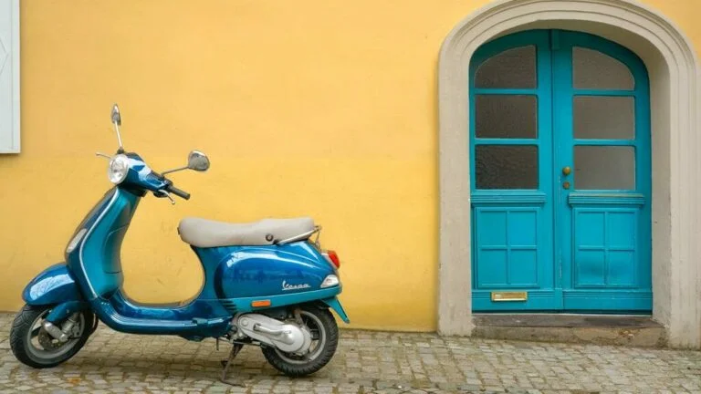 scooter verde parada perto de uma porta verde e uma parede amarela