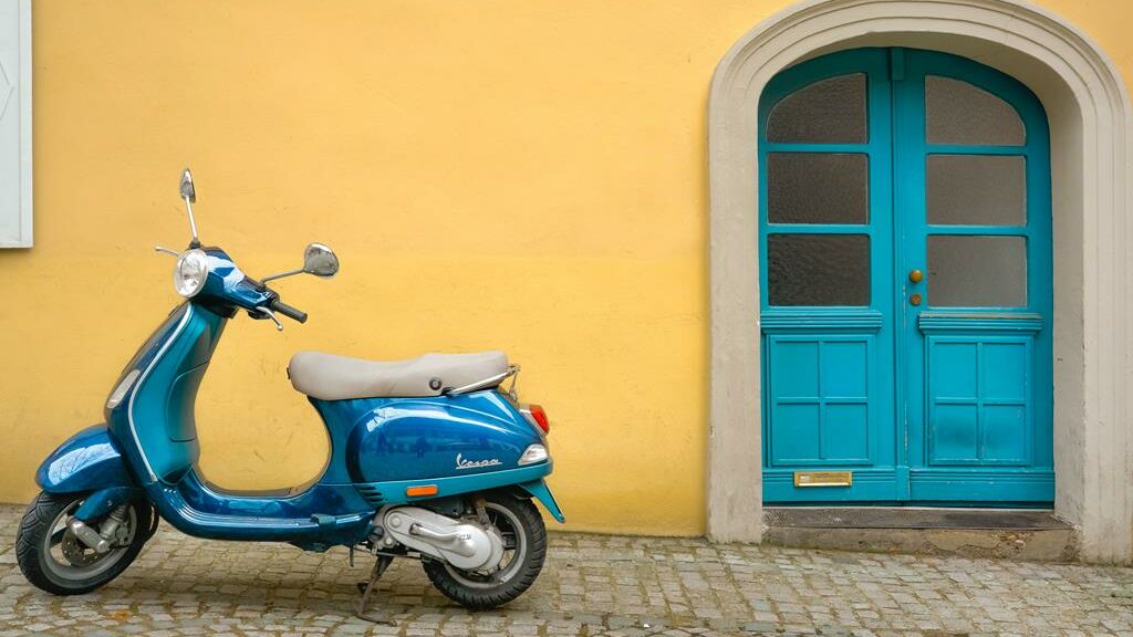 scooter verde parada perto de uma porta verde e uma parede amarela