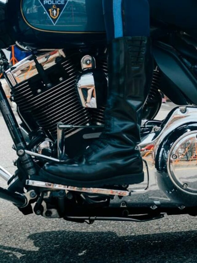 bota de motoqueiro preta no pedal de uma moto prata e escura da polícia