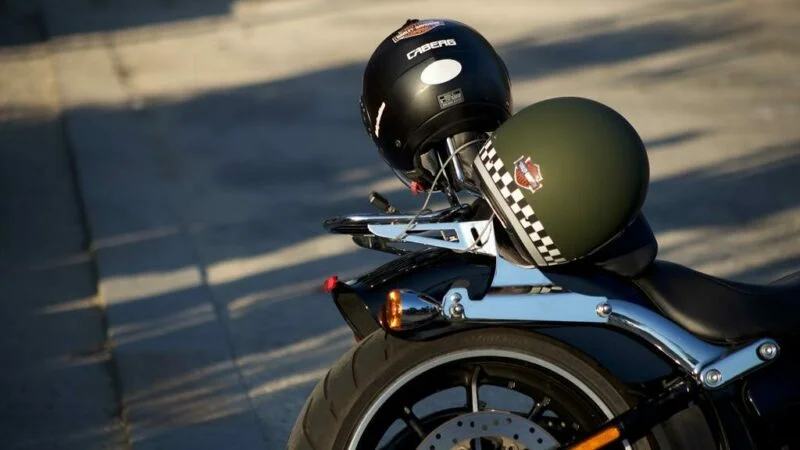 Dois capacetes, um preto e um verde, em cima de uma moto